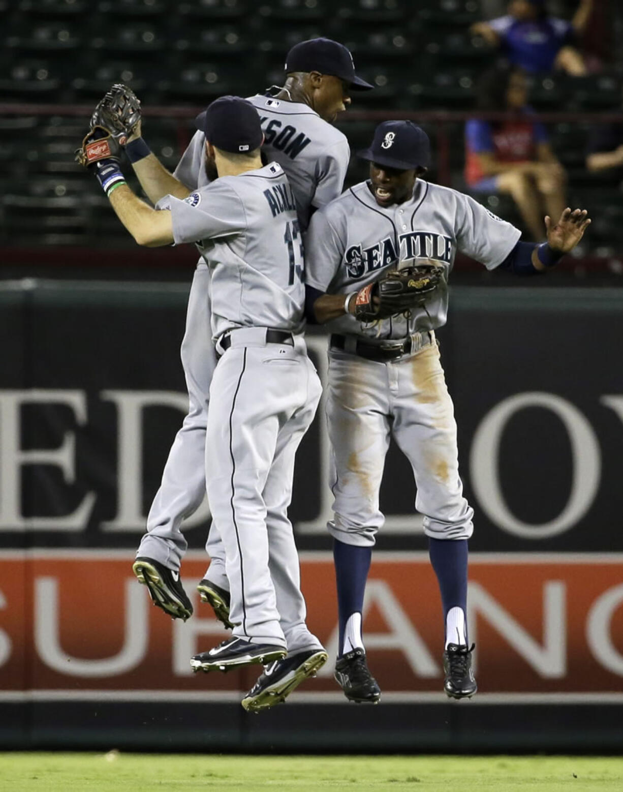 Seattle Mariners left fielder Dustin Ackley (13), center fielder Austin Jackson and right fielder James Jones, right, celebrate the Mariners' 7-5 win over the Texas Rangers in a baseball game, Friday, Sept. 5, 2014, in Arlington, Texas.