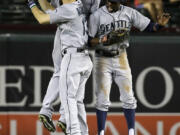 Seattle Mariners left fielder Dustin Ackley (13), center fielder Austin Jackson and right fielder James Jones, right, celebrate the Mariners' 7-5 win over the Texas Rangers in a baseball game, Friday, Sept. 5, 2014, in Arlington, Texas.