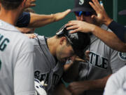 Seattle Mariners' Mike Zunino, center, is congratulated by his teammates in the dugout after hitting a home run against the Kansas City Royals in the seventh inning of a baseball game at Kauffman Stadium in Kansas City, Mo., Sunday, June 22, 2014. (AP Photo/Colin E.