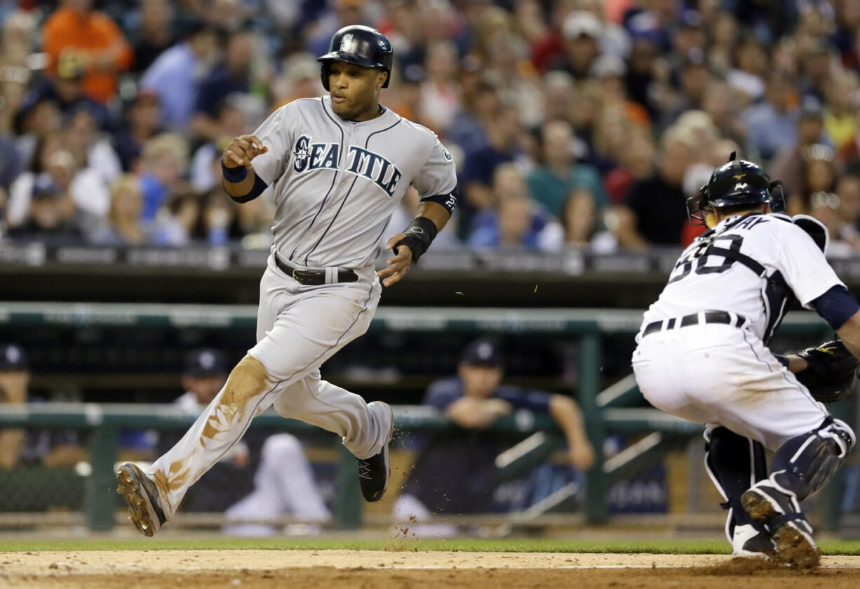 Seattle Mariners' Robinson Cano safely avoids the tag of Detroit Tigers catcher Bryan Holaday, right, and scores during the fifth inning of a baseball game, Friday, Aug. 15, 2014 in Detroit.