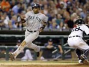 Seattle Mariners' Robinson Cano safely avoids the tag of Detroit Tigers catcher Bryan Holaday, right, and scores during the fifth inning of a baseball game, Friday, Aug. 15, 2014 in Detroit.