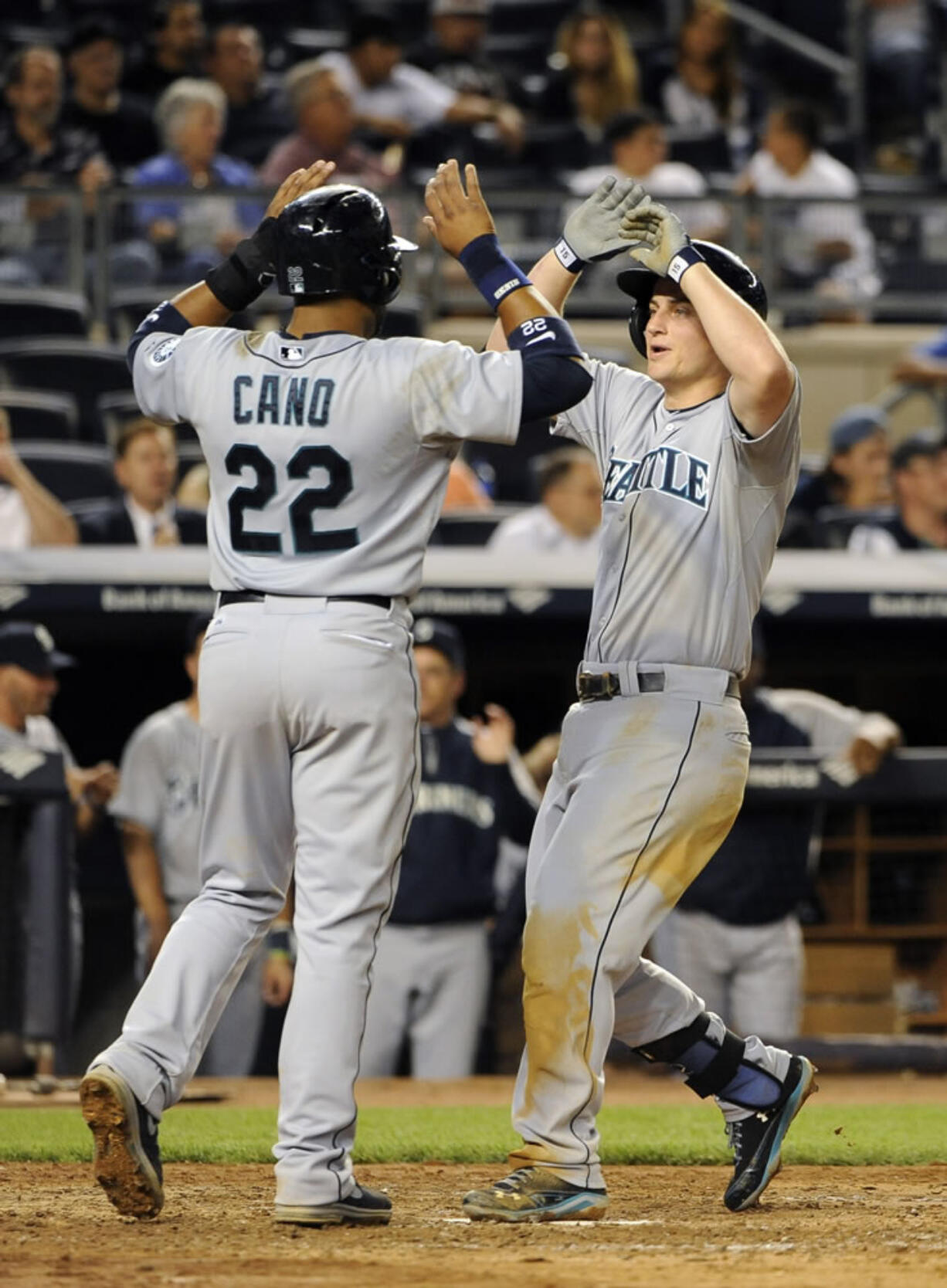 Seattle Mariners' Robinson Cano (22) greets Kyle Seager at home plate after Seager hit a three-run home run off of New York Yankees relief pitcher Alfredo Aceves that also scored Justin Smoak in the ninth inning Monday. The Mariners won 10-2.