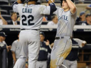 Seattle Mariners' Robinson Cano (22) greets Kyle Seager at home plate after Seager hit a three-run home run off of New York Yankees relief pitcher Alfredo Aceves that also scored Justin Smoak in the ninth inning Monday. The Mariners won 10-2.