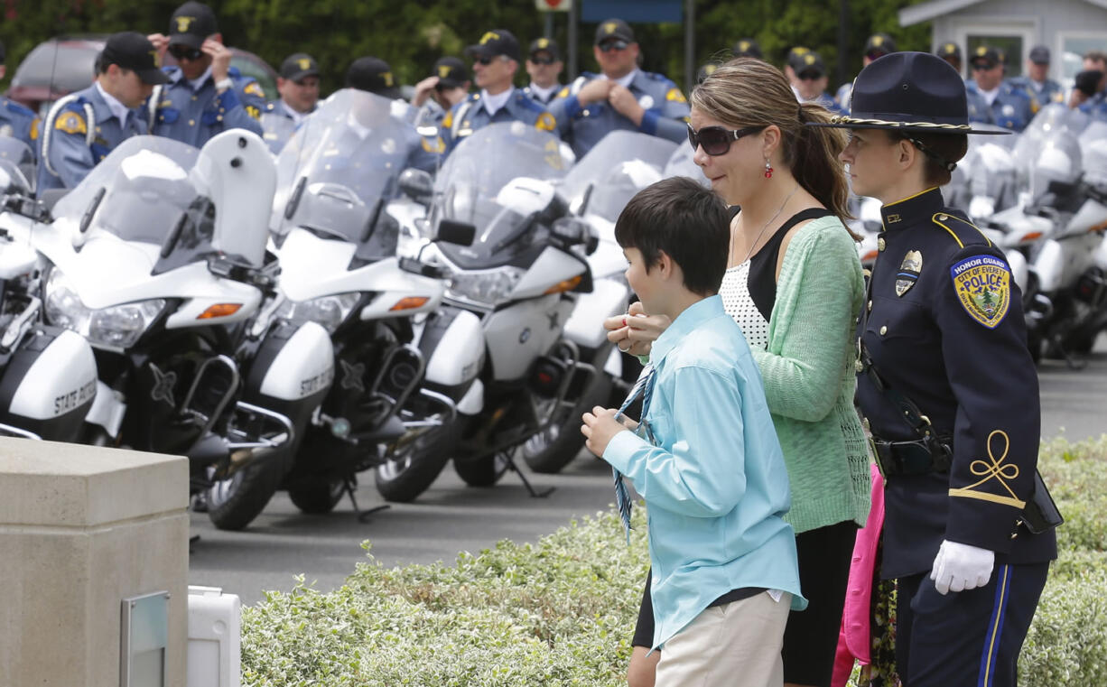 An Everett Police honor guard member, right, escorts Alissa O'Connell, second from right, and her son, Kian, 8, to their seats.