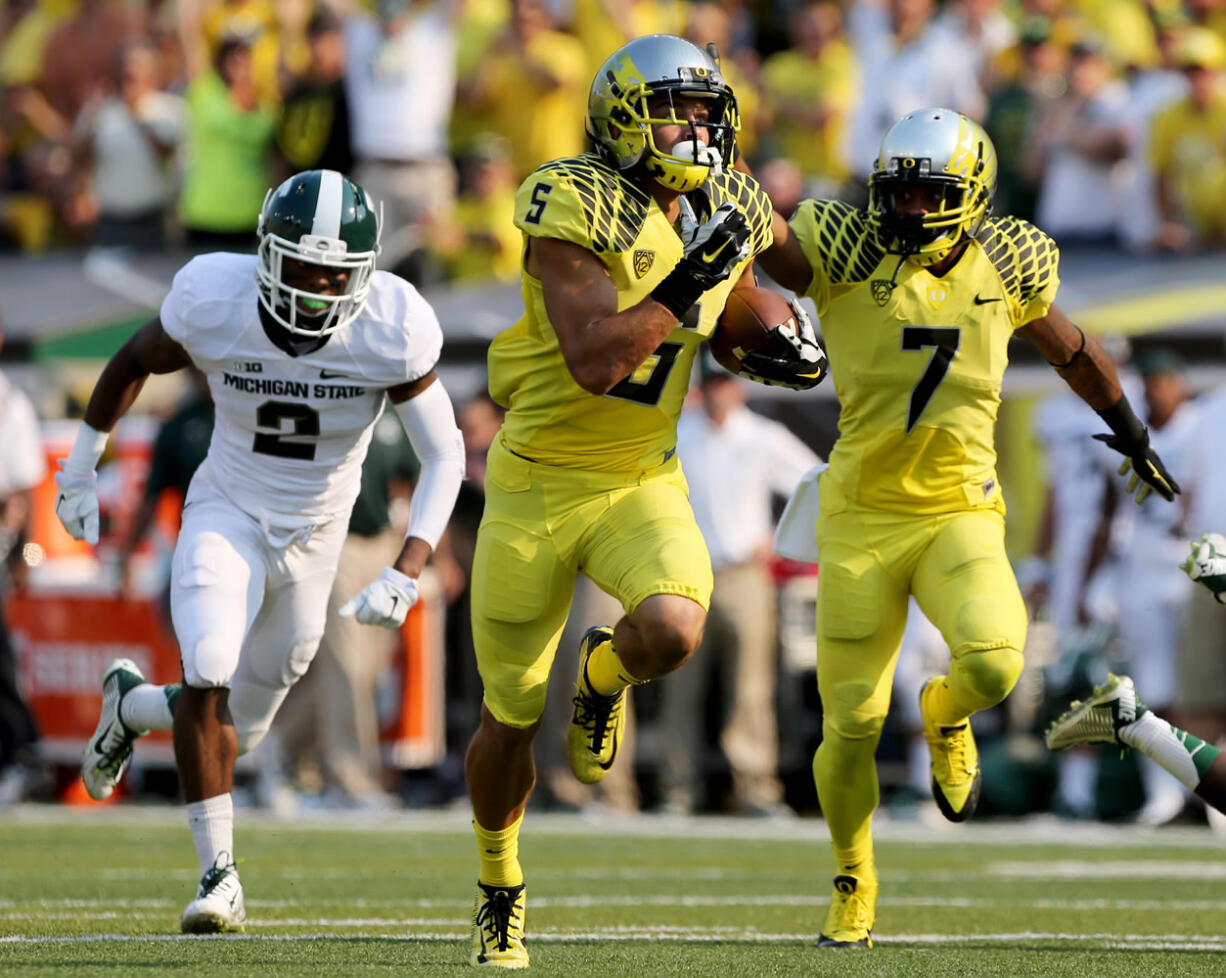 With Michigan State's Darian Hicks, left, in pursuit, Oregon's Devon Allen, center, runs to the end zone with teammate Keanon Lowe providing blocking during the 2nd quarter of their college football game in Eugene, Oregon, Saturday Sept. 6, 2014.