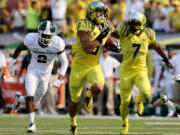 With Michigan State's Darian Hicks, left, in pursuit, Oregon's Devon Allen, center, runs to the end zone with teammate Keanon Lowe providing blocking during the 2nd quarter of their college football game in Eugene, Oregon, Saturday Sept. 6, 2014.