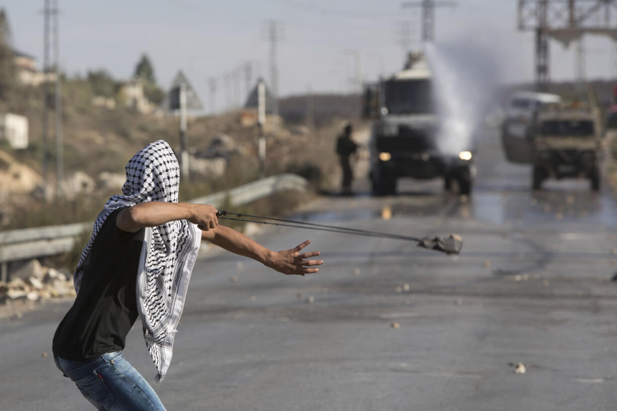 A Palestinian uses a sling shot to throw stones towards Israeli during clashes in Jalazoun refugee camp, near the West Bank city of Ramallah, Friday, Sept. 18, 2015. Palestinian protesters continued clashing with Israeli security forces on Friday in various parts of the West Bank and east Jerusalem. Israeli troops fired tear gas, stun grenades and deployed a water cannon to disperse stone-throwing Palestinian youths. Friday's clashes follow days of unrest at Jerusalem's hilltop compound known to the Muslims as the Noble Sanctuary and to Jews as the Temple Mount.