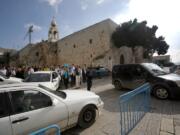 Tourists walk and cars drive past the Church of the Nativity in Bethlehem, West Bank.