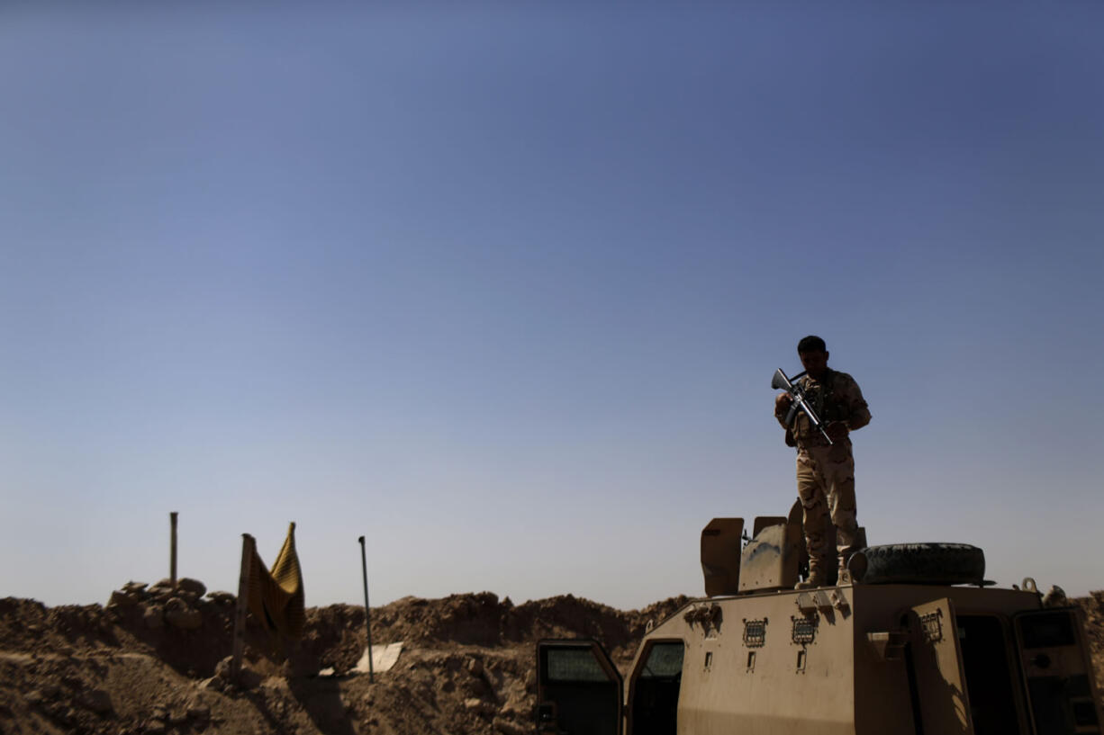 A Kurdish Peshmerga fighter stands guard atop an armored vehicle at a combat outpost on the outskirts of Makhmour, 186 miles north of Baghdad, Iraq, on Saturday.