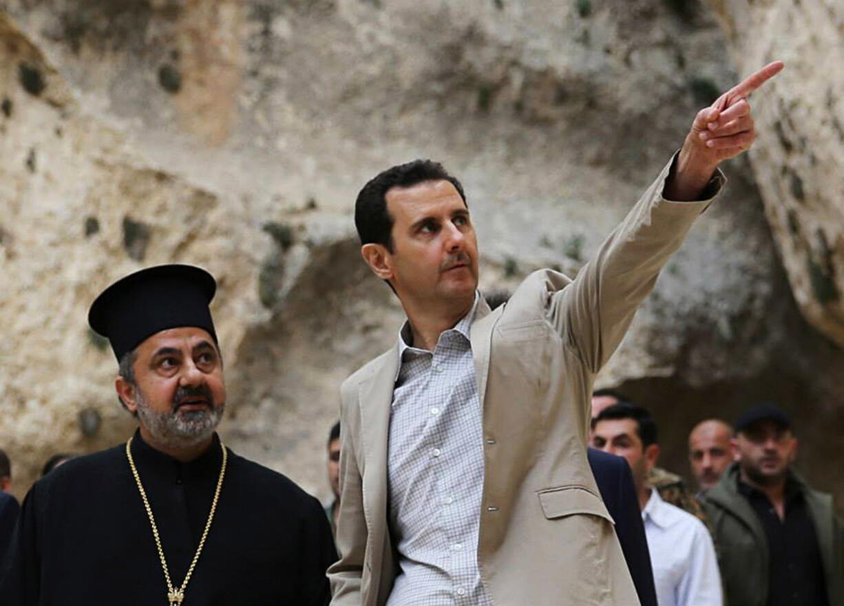 In this photo released by the Syrian official news agency SANA, Syrian President Bashar Assad, right, visits the Christian village of Maaloula, near Damascus, Syria, in April.