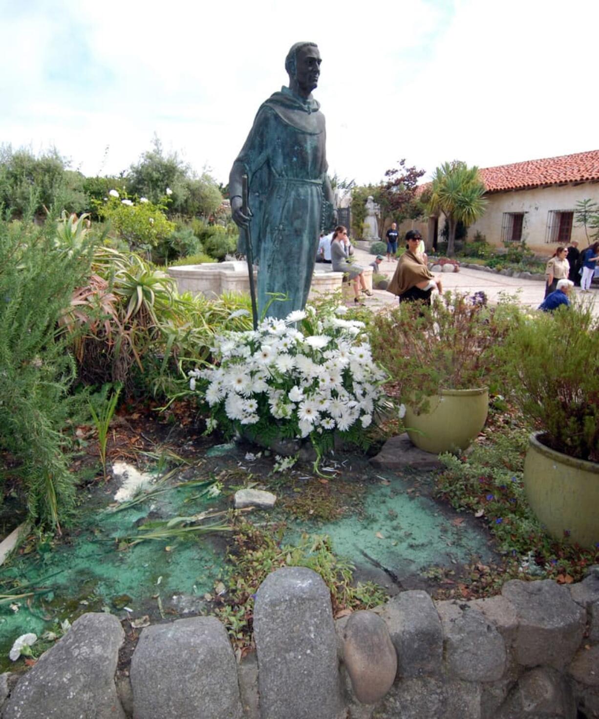 Green paint lies pooled Sunday at the foot of the statue of Father Junipero Serra at the Carmel Mission, where the remains of the recently canonized missionary are buried in Carmel, Calif. Vandals defaced a statue of Serra.