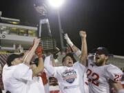 Southern Oregon players, including quarterback Austin Dodge, second from right, and linebacker Heston Altenbach (22), celebrate with the trophy after winning the NAIA championship football game against Marian, 55-31, in Daytona Beach, Fla.