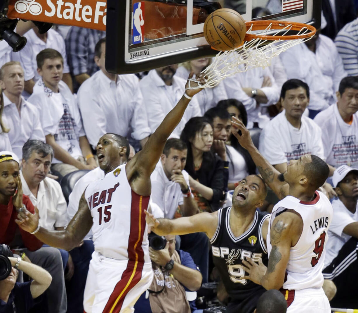 Miami Heat guard Mario Chalmers (15) blocks a shot to the basket by San Antonio Spurs guard Tony Parker (9) as Rashard Lewis (9) defends during Game 3 of the NBA Finals Tuesday in Miami.