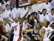 Miami Heat guard Mario Chalmers (15) blocks a shot to the basket by San Antonio Spurs guard Tony Parker (9) as Rashard Lewis (9) defends during Game 3 of the NBA Finals Tuesday in Miami.