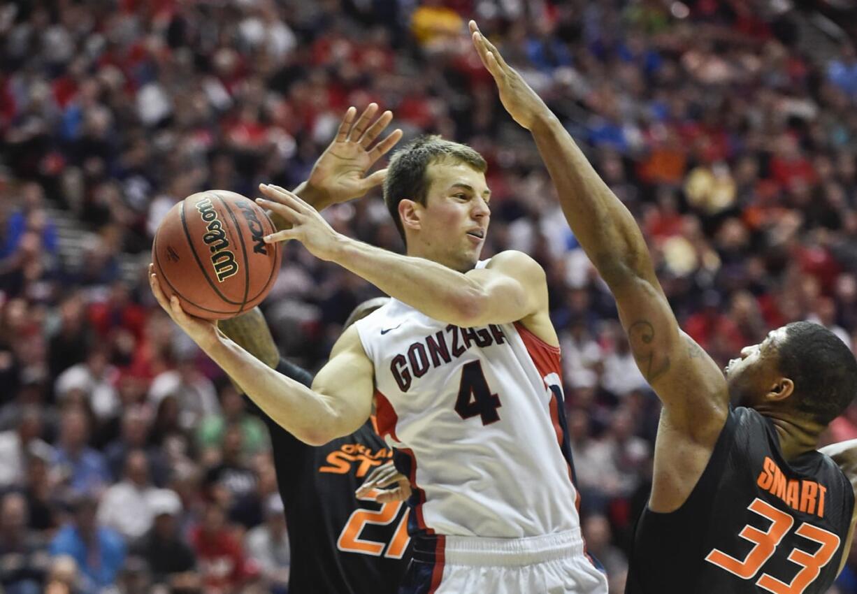 Gonzaga guard Kevin Pangos splits Oklahoma State defenders Kamari Murphy, left, and Marcus Smart while looking to pass during the first half in a second-round game in the NCAA college basketball tournament Friday, March 21, 2014, in San Diego.