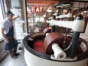 Scott Witherow, founder and owner of Olive and Sinclair Chocolate, operates his stone grinders to grind cacao beans April 6 in the East Nashville area of Nashville, Tenn.