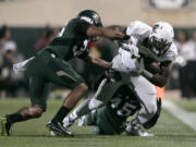 Oregon's Royce Freeman, right, is tackled by Michigan State's Darien Harris (45) and Arjen Colquhoun, left, during the first quarter of an NCAA college football game, Saturday, Sept. 12, 2015, in East Lansing, Mich.