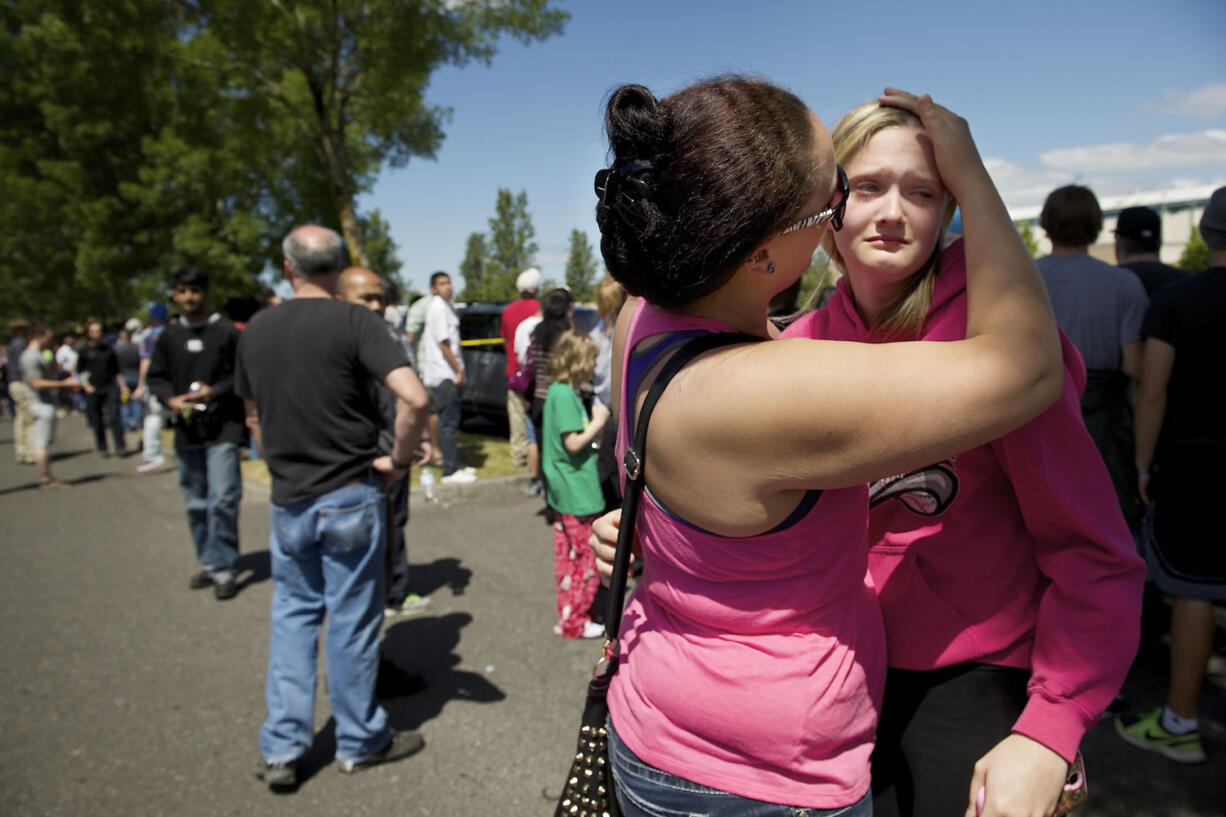 Briannah Wilson, 21, left, comforts her sister, Trisha Wilson, right, 15, as students are reunited with family at a shopping center parking lot in Wood Village, Ore., after a shooting at Reynolds High School on Tuesday in nearby Troutdale.