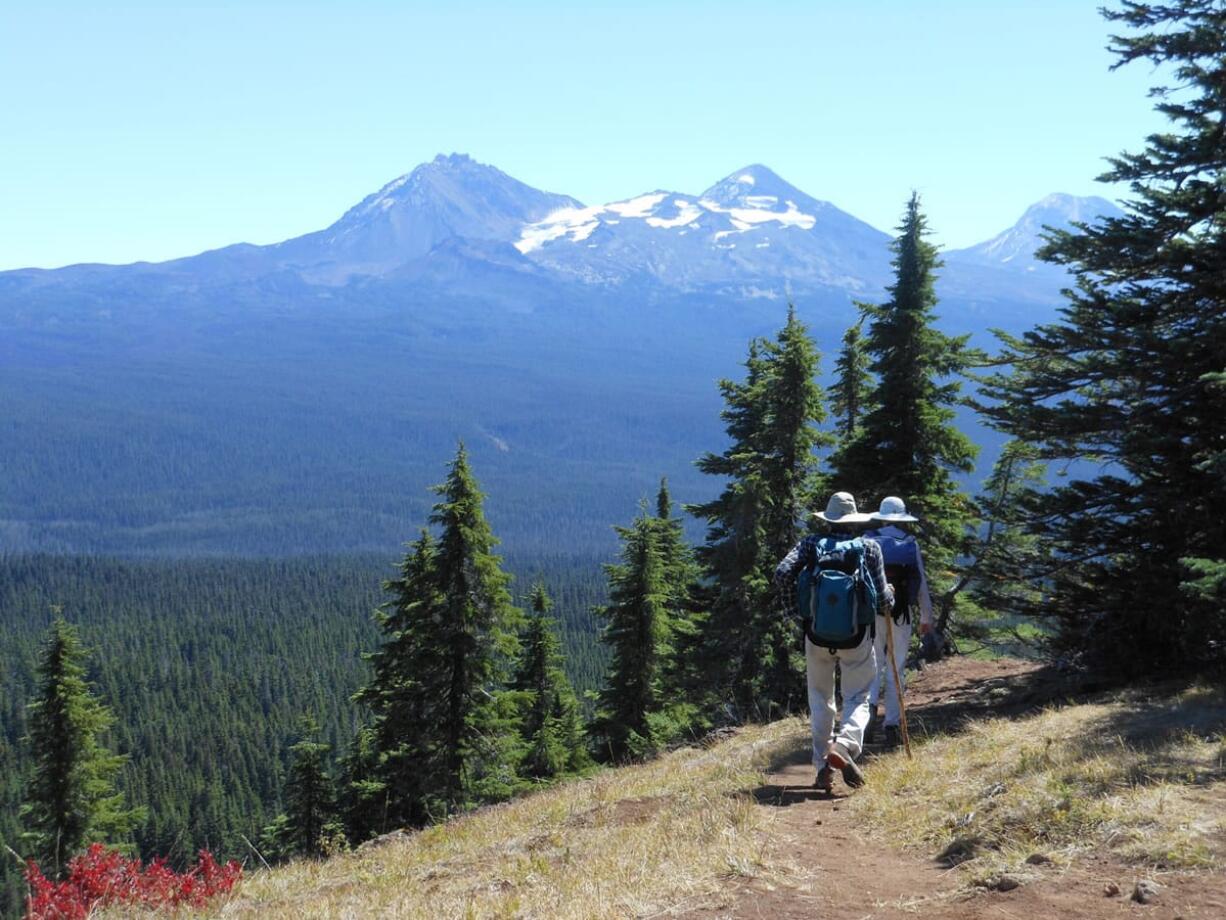 With the Three Sisters in the background, hikers make their way along the summit of Scott Mountain near McKenzie Pass, Ore. Central Oregon is home to so many inviting trails it can be downright daunting to determine the best option for a day hike.