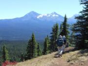 With the Three Sisters in the background, hikers make their way along the summit of Scott Mountain near McKenzie Pass, Ore. Central Oregon is home to so many inviting trails it can be downright daunting to determine the best option for a day hike.