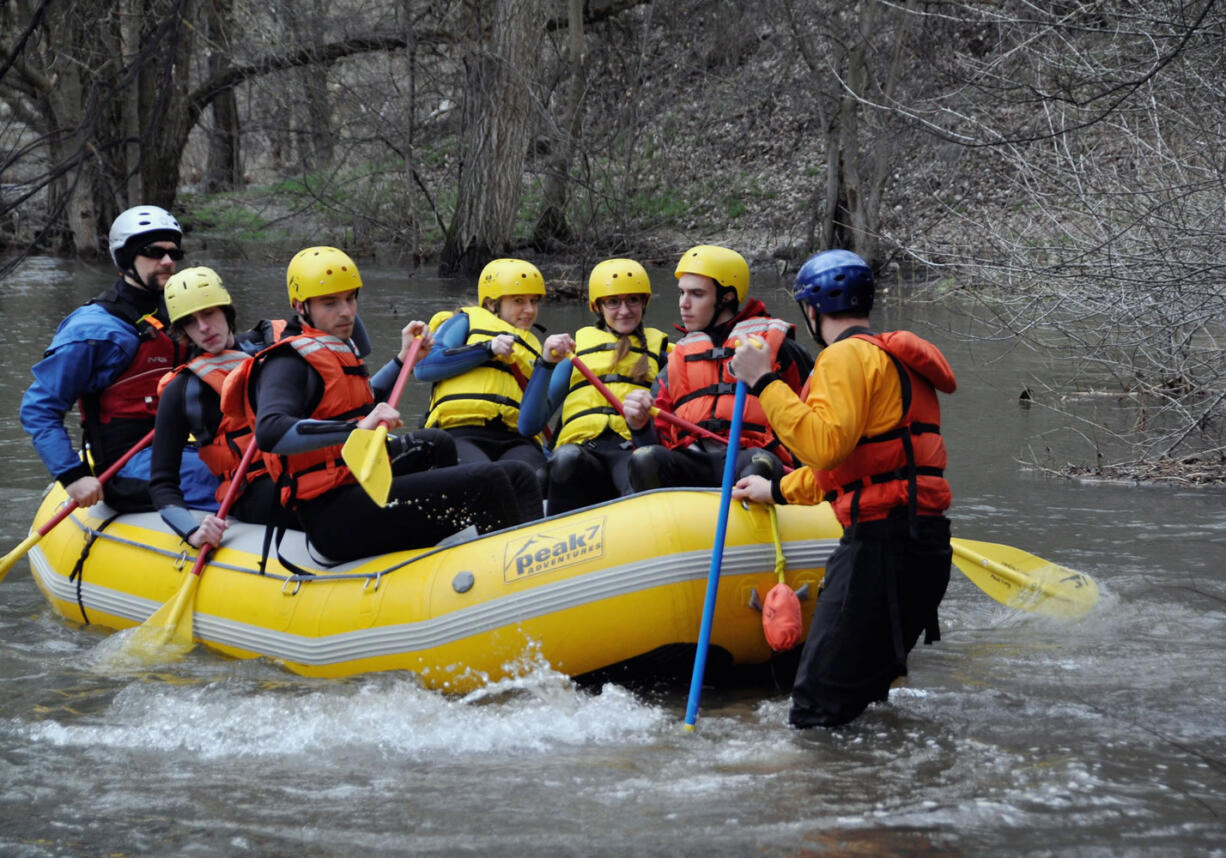 Mock volunteers learn to paddle from a Peak 7 Adventures guide-in-training session as they prepare to launch their raft on the Spokane River.