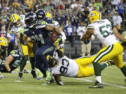 Seattle Seahawks running back Marshawn Lynch, left, runs for a touchdown against the Green Bay Packers in the second half of an NFL football game, Thursday, Sept. 4, 2014, in Seattle.