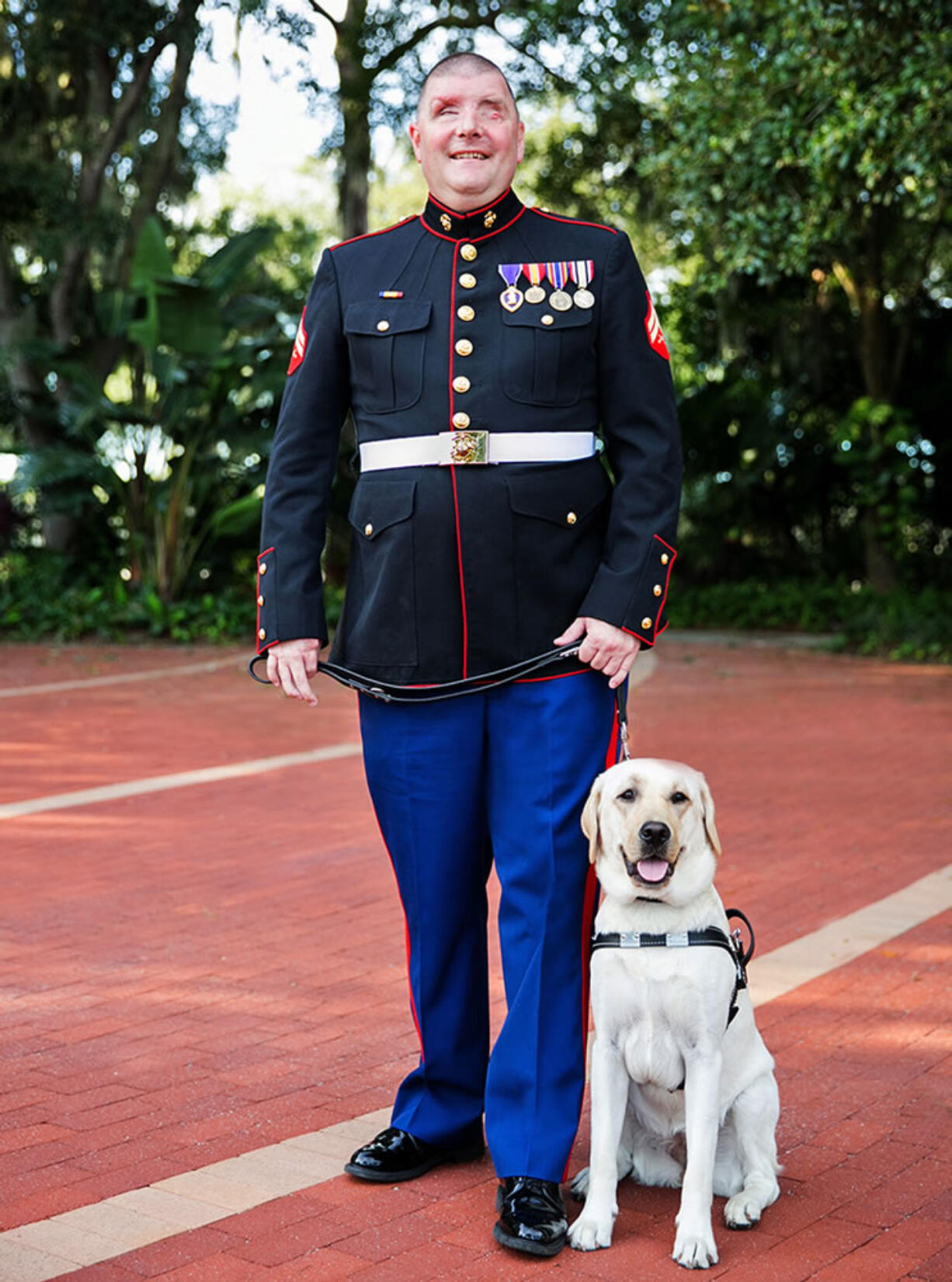 In this Aug. 17, 2015 photo provided by Southeastern Guide Dogs, Michael Jernigan poses with his guide dog Treasure on the campus of Southeastern Guide Dogs in Palmetto, Fla. Jernigan lost his eyesight and part of his brain when a roadside bomb ripped into his Humvee in Iraq in 2004. He has undergone more than 30 surgeries. But he insists, thanks to a couple of dogs, he found more than he lost.