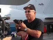 Yahuda Netanel, a private pilot with Wings of Rescue, holds a rescue dog as he stands by his plane prior to a flight at Van Nuys Airport, in Van Nuys, Calif.