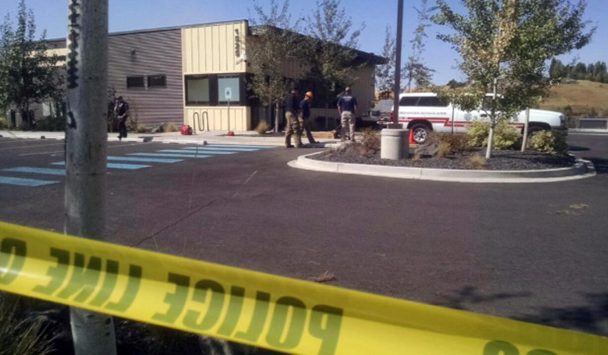 Police and fire investigators stand near the Planned Parenthood clinic in Pullman after it was damaged by a fire Friday. The pre-dawn fire heavily damaged the clinic in the college town and a regional terrorism task force is working to determine whether it was arson.