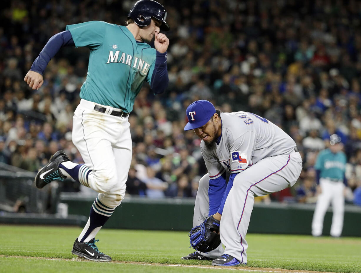 Seattle Mariners' Brad Miller, left, watches as Texas Rangers starting pitcher Yovani Gallardo fields Miller's ground ball along the first base line during the fifth inning Friday, April 17, 2015, in Seattle. Gallardo completed the play, throwing Miller out at first to end the inning.