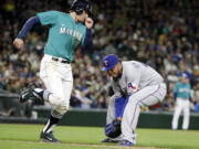 Seattle Mariners' Brad Miller, left, watches as Texas Rangers starting pitcher Yovani Gallardo fields Miller's ground ball along the first base line during the fifth inning Friday, April 17, 2015, in Seattle. Gallardo completed the play, throwing Miller out at first to end the inning.