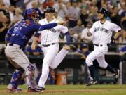 Seattle Mariners' Logan Morrison, center, is followed closely by Chris Taylor as the pair head home past Texas Rangers catcher Robinson Chirinos in the fourth inning of a baseball game Tuesday, Aug. 26, 2014, in Seattle.