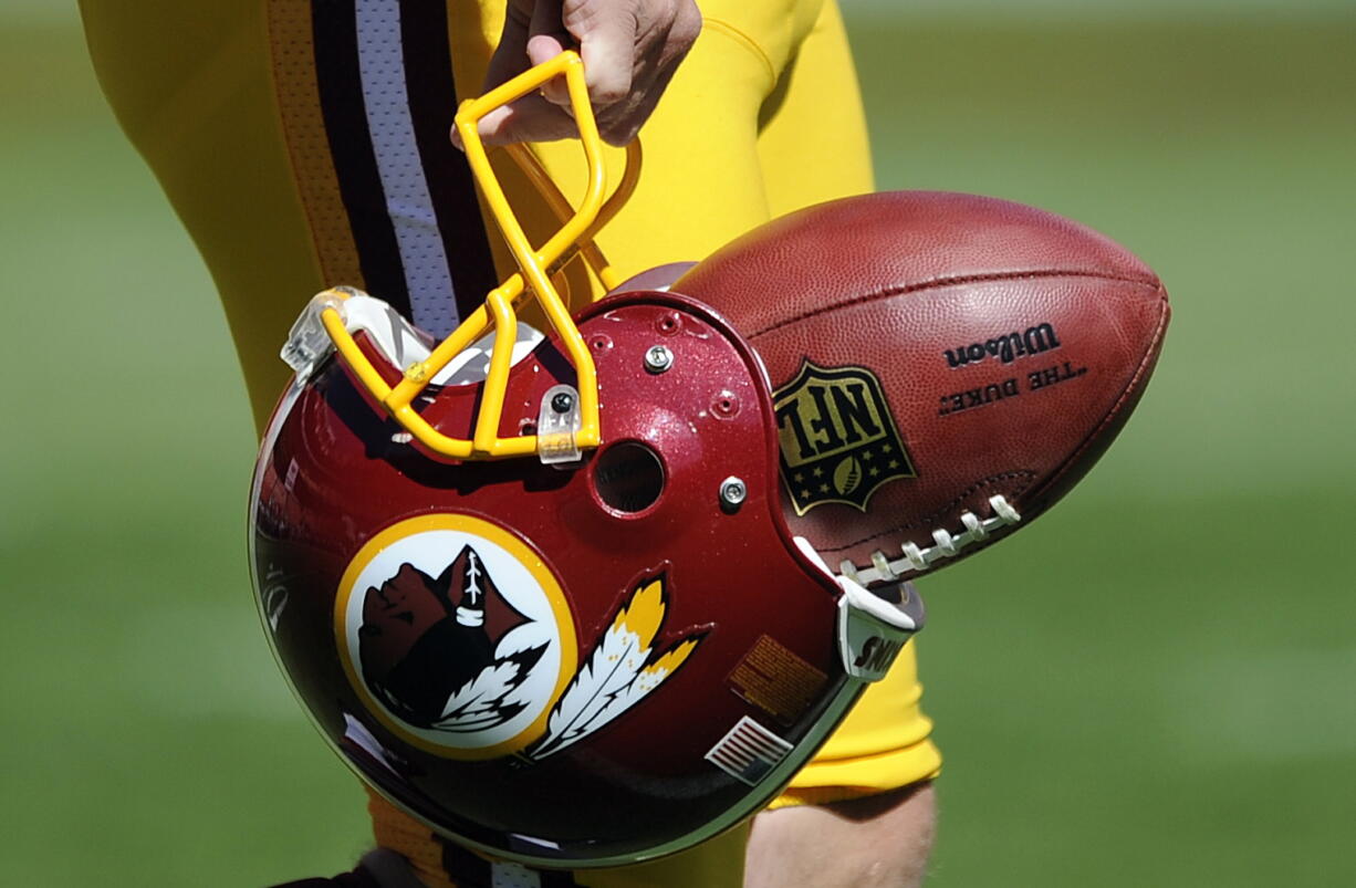 Washington Redskins punter Sav Rocca carries a football in his helmet Sept. 23, 2012before an NFL football game against the Cincinnati Bengals in Landover, Md. The U.S. Patent Office ruled Wednesday that the Washington Redskins nickname is &quot;disparaging of Native Americans&quot; and that the team's federal trademarks for the name must be canceled.