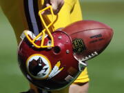 Washington Redskins punter Sav Rocca carries a football in his helmet Sept. 23, 2012before an NFL football game against the Cincinnati Bengals in Landover, Md. The U.S. Patent Office ruled Wednesday that the Washington Redskins nickname is &quot;disparaging of Native Americans&quot; and that the team's federal trademarks for the name must be canceled.