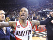 Portland Trail Blazers' Damian Lillard, center, celebrates with fans, his winning shot against the Houston Rockets during the last .9 of a second of game six of an NBA basketball first-round playoff series game in Portland, Ore., Friday May 2, 2014. The Trail Blazers won the series in a 99-98 win.