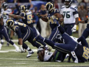 Seattle Seahawks running back Marshawn Lynch lands on his back as he is stopped on fourth down and St. Louis Rams players celebrate on the final play in overtime of an NFL football game Sunday, Sept. 13, 2015, in St. Louis. The Rams won 34-31.