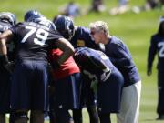 Seattle Seahawks head coach Pete Carroll listens in on a huddle during NFL football minicamp Thursday, June 19, 2014, in Renton, Wash.