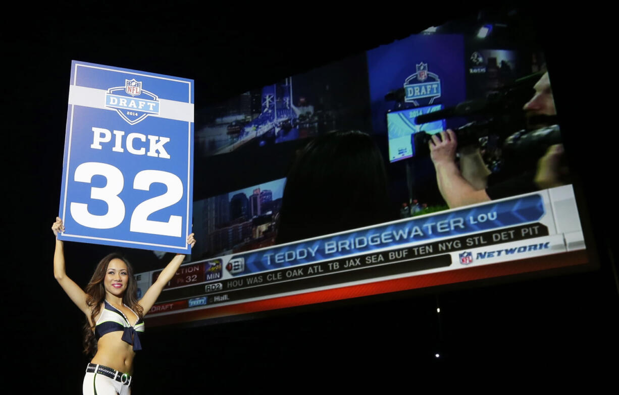 A Seattle Seahawks Sea Gals cheerleader carries a sign to announce the 32nd pick in the first round of the NFL football draft, which the Super Bowl champion Seattle Seahawks traded to the Minnesota Vikings, who selected Louisville quarterback Teddy Bridgewater.