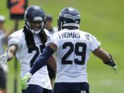 Seattle Seahawks cornerback Richard Sherman, left, reacts to a play with free safety Earl Thomas, right, during a practice drill at an NFL football organized team activity, Monday, June 9, 2014 in Renton, Wash. (AP Photo/Ted S.