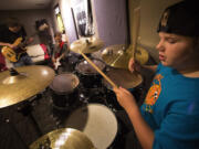 Under the instruction of Philip Gustason, left, general manager at the School of Rock in Seattle, Ro'ya Mottaghinejad, 8, back right, and Wade Beeler, right, jam together in a day camp at the school while Seattle teachers are on strike on Monday, Sept. 14, 2015. (Ellen M.