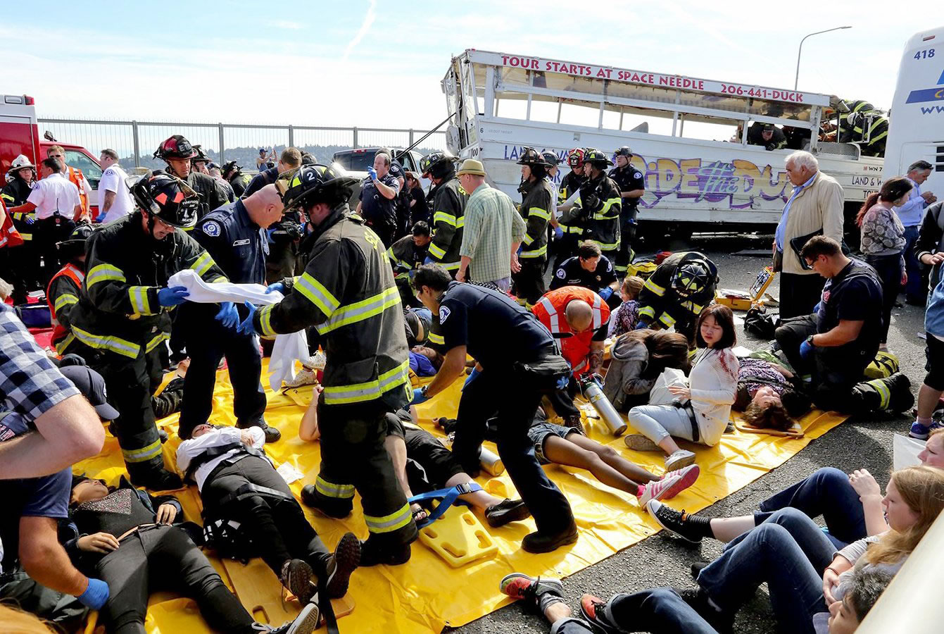 Emergency personnel work at the scene of a fatal collision involving a charter bus, background, and a "Ride the Ducks" amphibious tour bus, right, on the Aurora Bridge in Seattle on Thursday.