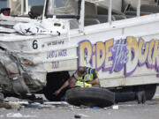 Seattle Police officers look under a &quot;Ride the Ducks&quot; tourist vehicle as a tire and wheel from the bus sits nearby before the bus is loaded onto a flatbed tow truck Thursday, Sept. 24, 2015, after it was involved in a fatal crash with a charter passenger bus earlier in the day in Seattle. (AP Photo/Ted S.