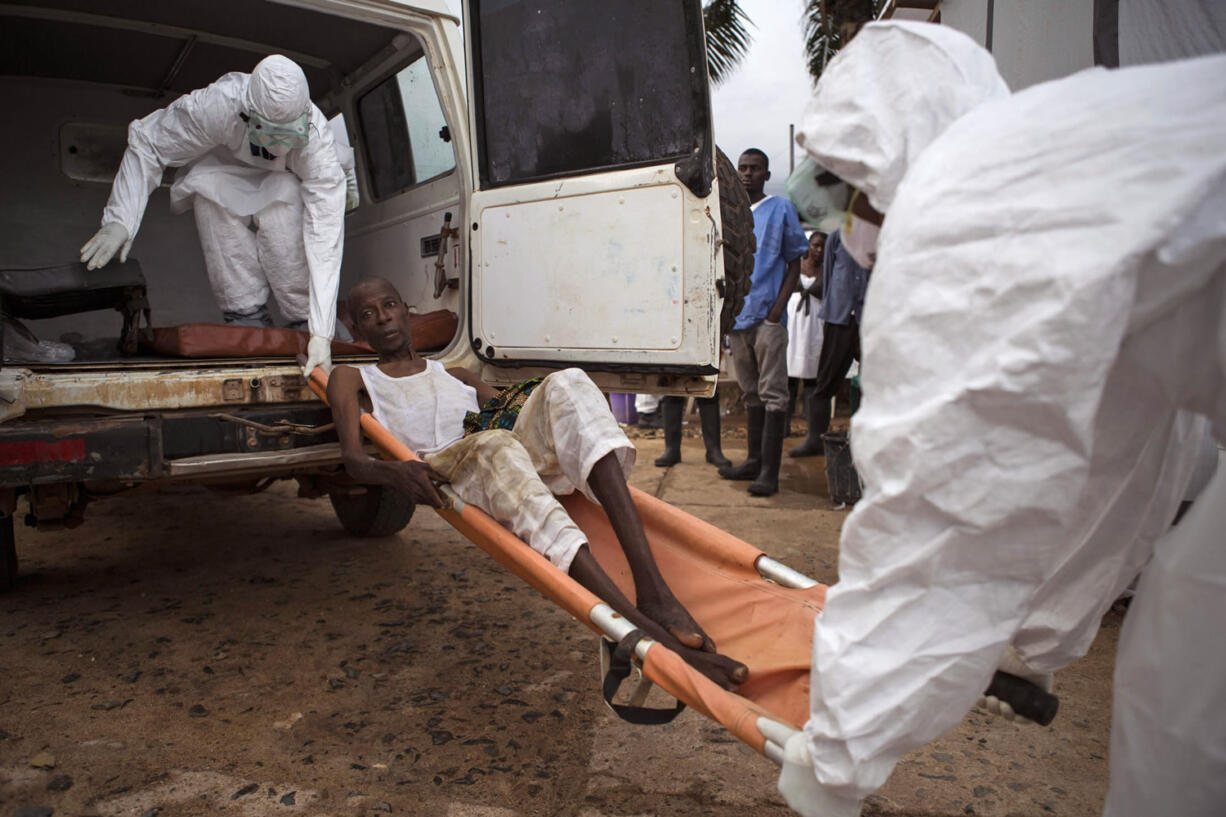 Health care workers load a man, center, onto a ambulance as he is  suspected of suffering from the Ebola virus in Kenema, Sierra Leone.