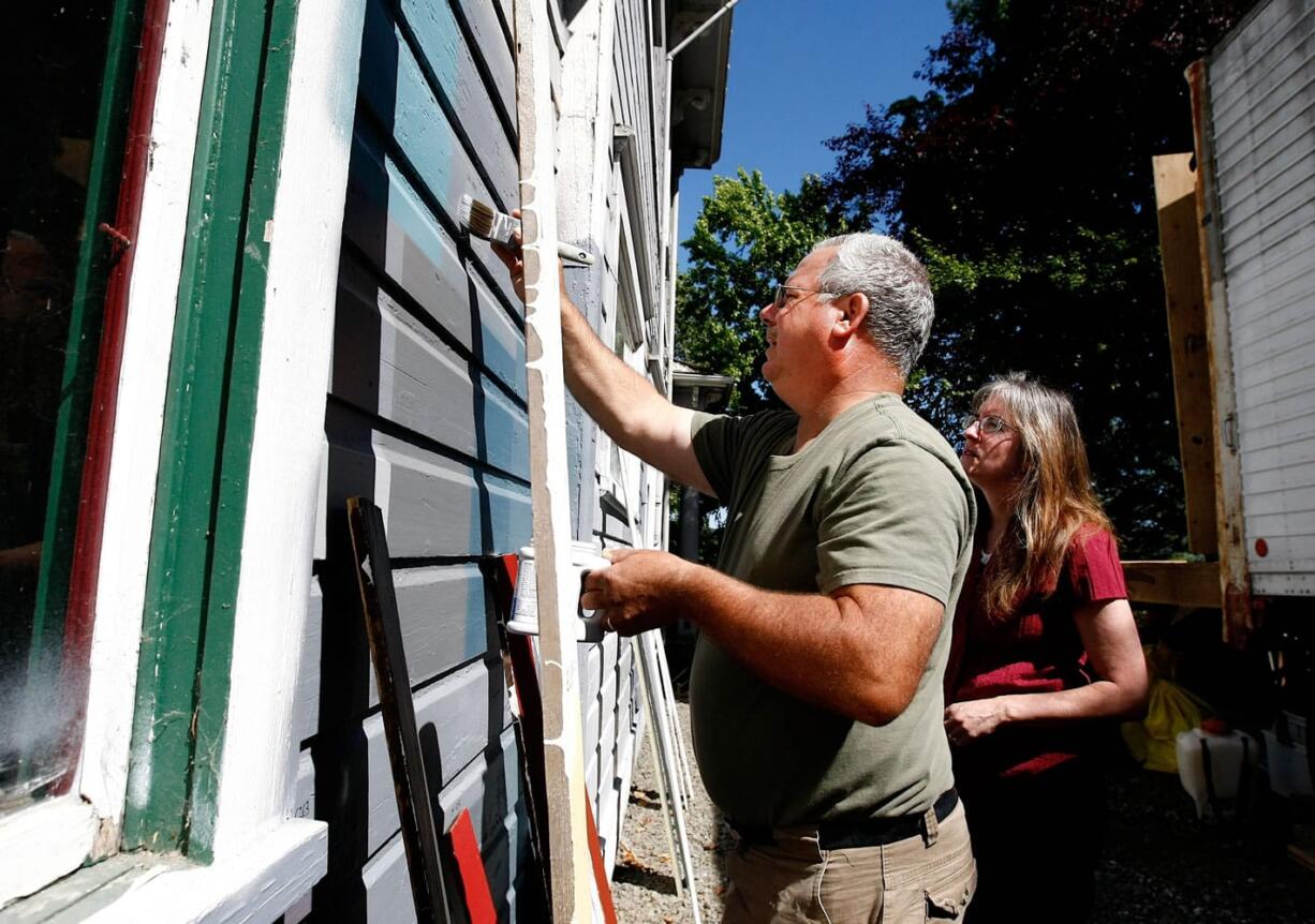 Gordon Forbes and his wife, Lynn, paint sample swatches June 19 onto a home they bought in Oakland, Ore.