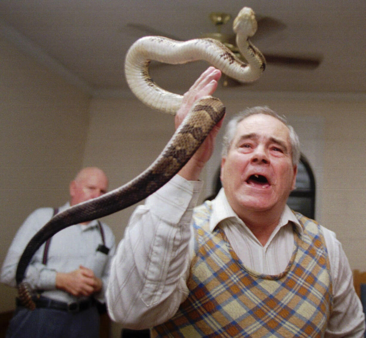 Associated Press files
Junior McCormick tests his faith by handling a rattlesnake as Homer Browing looks on in 1995 during services at the Church of the Lord Jesus in Kingston, Ga. Church members believe that if they have faith in God, they will be protected from harm as they handle the serpents.