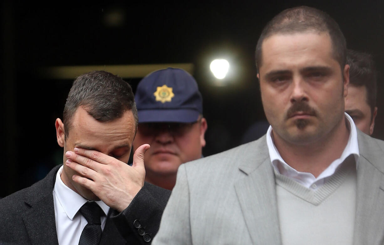 Oscar Pistorius, left, leaves the high court in Pretoria, South Africa on Monday.