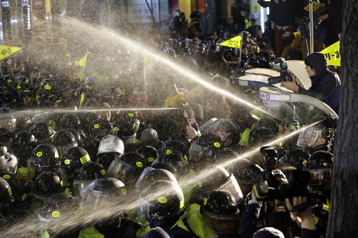 Police officers spray protesters trying to march after a rally commemorating the first anniversary of the Sewol ferry sinking Thursday in Seoul, South Korea.