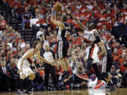 San Antonio Spurs' Tony Parker (9) shoots as Portland Trail Blazers' Robin Lopez (42) and Wesley Matthews (2) defend in the first quarter of Game 3 on Saturday.