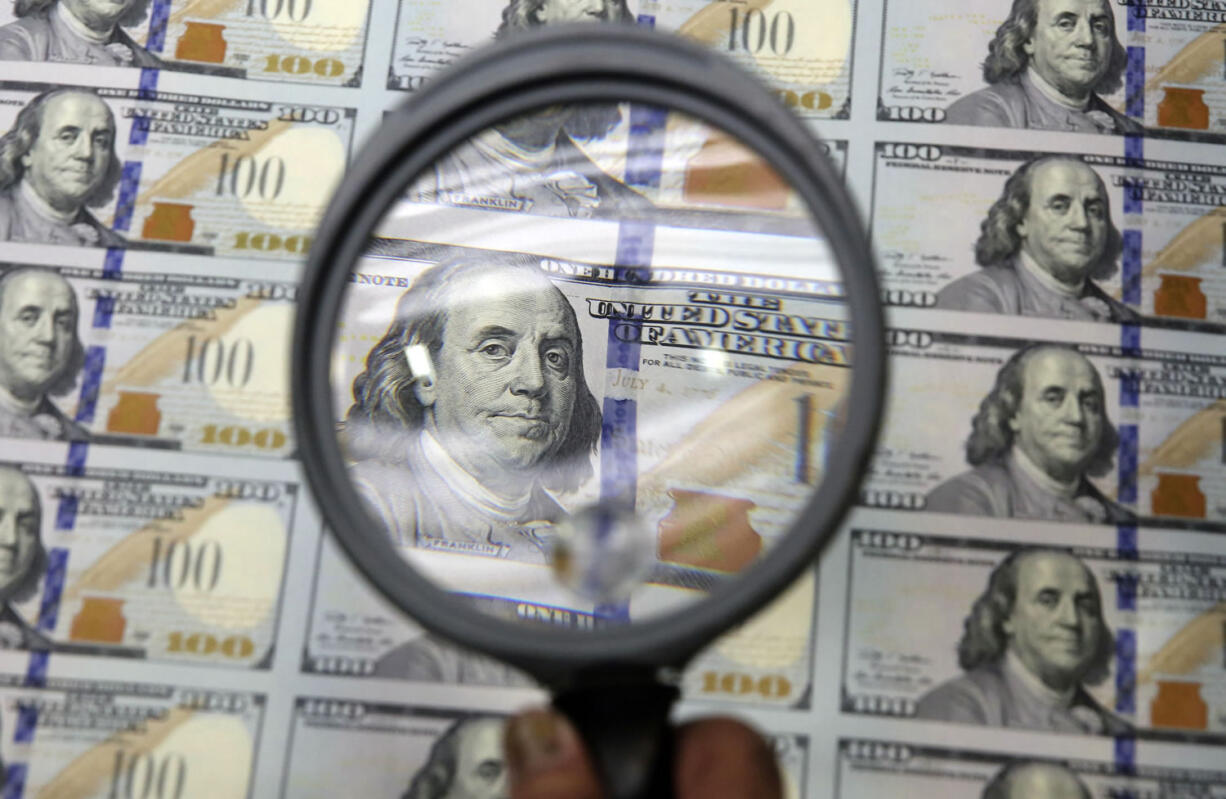 FILE - In this Sept. 24, 2014 file photo, a sheet of uncut $100 bills is inspected during the printing process at the Bureau of Engraving and Printing Western Currency Facility in Fort Worth, Texas. A strengthening U.S. economy, combined with a gloomy outlook for growth elsewhere in the world, is pushing the U.S. currency to its highest level in more than a year.