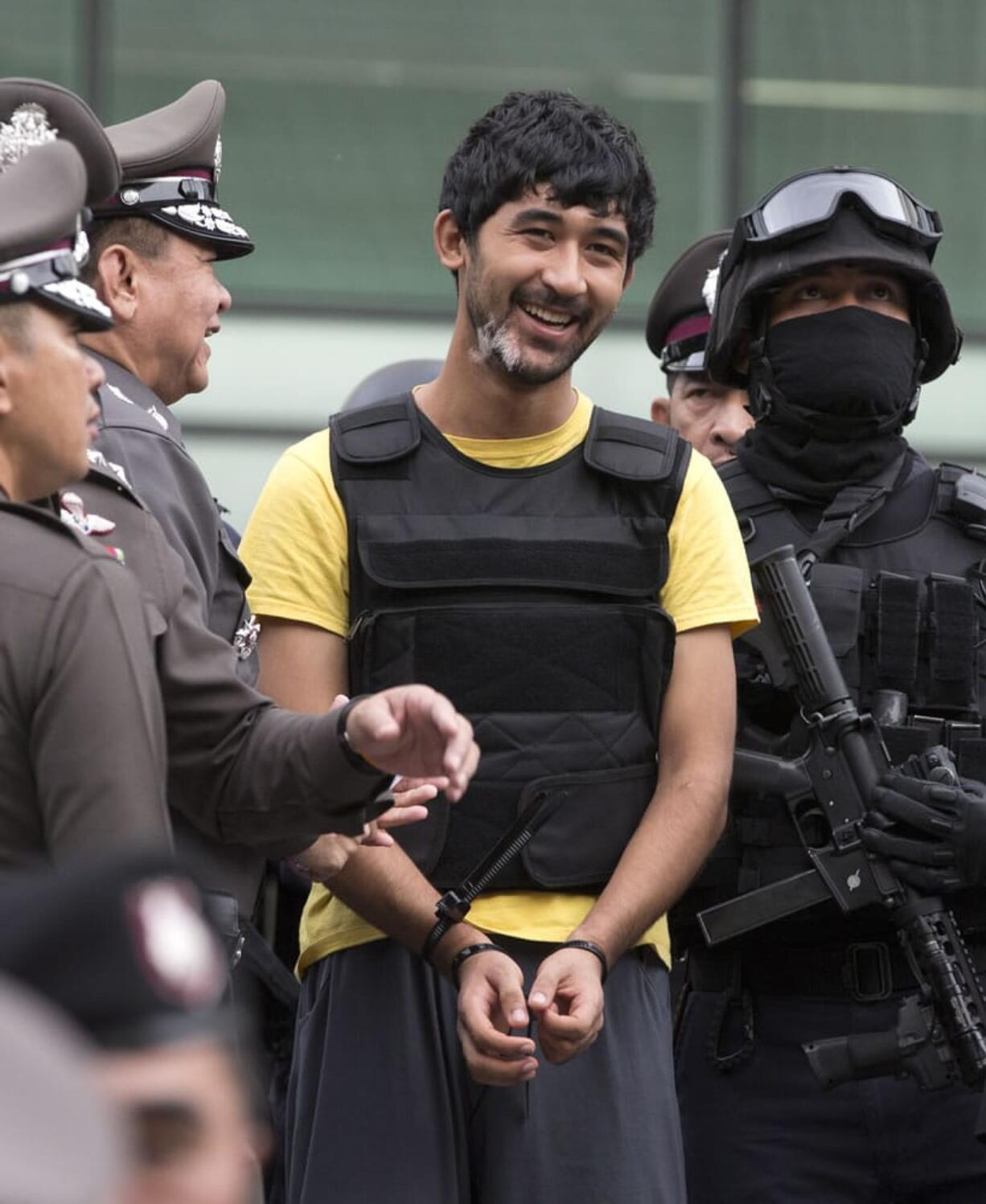 Police officers joke with a key suspect in last month's Bangkok bombing, center in yellow shirt, identified by Thai police as Yusufu Mierili, also as Yusufu Mieraili, traveling on a Chinese passport, but his nationality remains unconfirmed, around a central Bangkok shopping center during a reenactment for the Aug. 17 bombing at Bangkok's popular Erawan Shrine that left 20 people dead and more than 120 injured, Wednesday, Sept. 9, 2015.